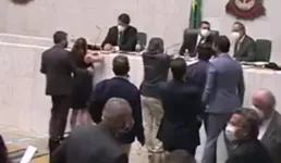 Nas imagens, Penna conversa com a mesa diretora, quando Cury se aproxima dela por trás e passa a mão em seus seios. A deputada imediatamente se desvia de Cury e o repele. 