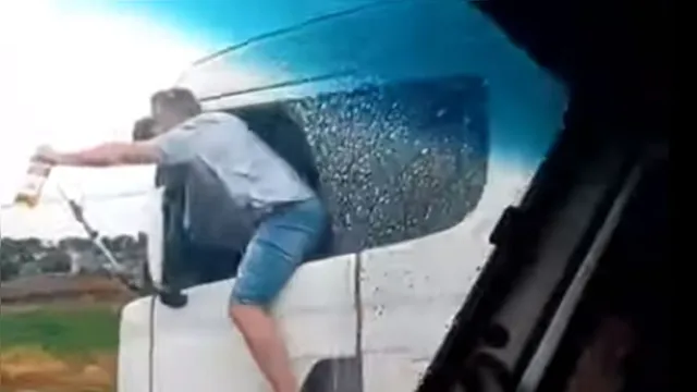 Imagem ilustrativa da notícia Vídeo: motorista se pendura para fora de caminhão com bebida nas mãos