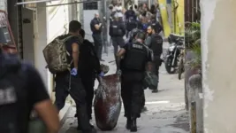 Policiais carregando os corpos durante a operação