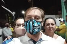 A servidora aparece sem máscara (ela está à direita do homem com máscara do Grêmio na imagem em destaque).