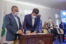 O prefeito Edmilson Rodrigues observa o governador Helder Barbalho assinar o termo que transfere R$ 5 milhões do Estado ao município