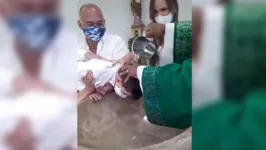 A criança "reclama" no momento em que está sendo batizada.