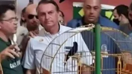 Em um galpão lotado de gaiolas de pássaros, Bolsonaro posou ao lado de apoiadores.