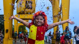 Menina abre os braços e o sorriso na fantasia da boneca Emília do Sítio do Picapau Amarelo no carnaval antes da pandemia