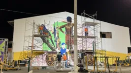 Artistas criam, coletivamente, um grande painel artístico usando técnicas como o grafite, a pintura, o desenho e o estêncil