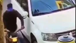 Criminoso esbarra no retrovisor, forçando a vítima a baixar o vidro do veículo.