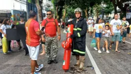 Bombeiro militar caminha pelas ruas da capital carregando uma cruz feita com extintores de incêndio