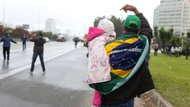 Criança no colo de responsável durante protesto na rodovia Castelo Branco, em Barueri, na Grande SP