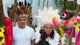 Gretechen e o marido aparecem vestidos de branco e de cocar na cabeça recebendo as bênçãos de uma sacerdote indígena.