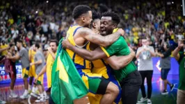 Jogadores da seleção brasileira de basquete comemoram classificação com membro da comissão técnica.