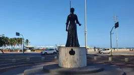 Monumento na cidade do Rio de Janeiro (RJ). Escultura da Princesa Isabel em bronze acima de base cilíndrica branca, estendendo mão para a frente