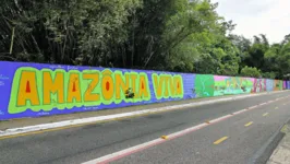 Mural traz referências sobre a identidade amazônida e a força das mulheres locais. Abaixo, a artista visual Lenu