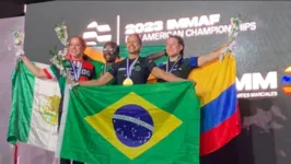 Josiane Lima no topo do pódio com a medalha de ouro e a bandeira do Brasil.