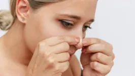 Mulher espremendo espinha no nariz