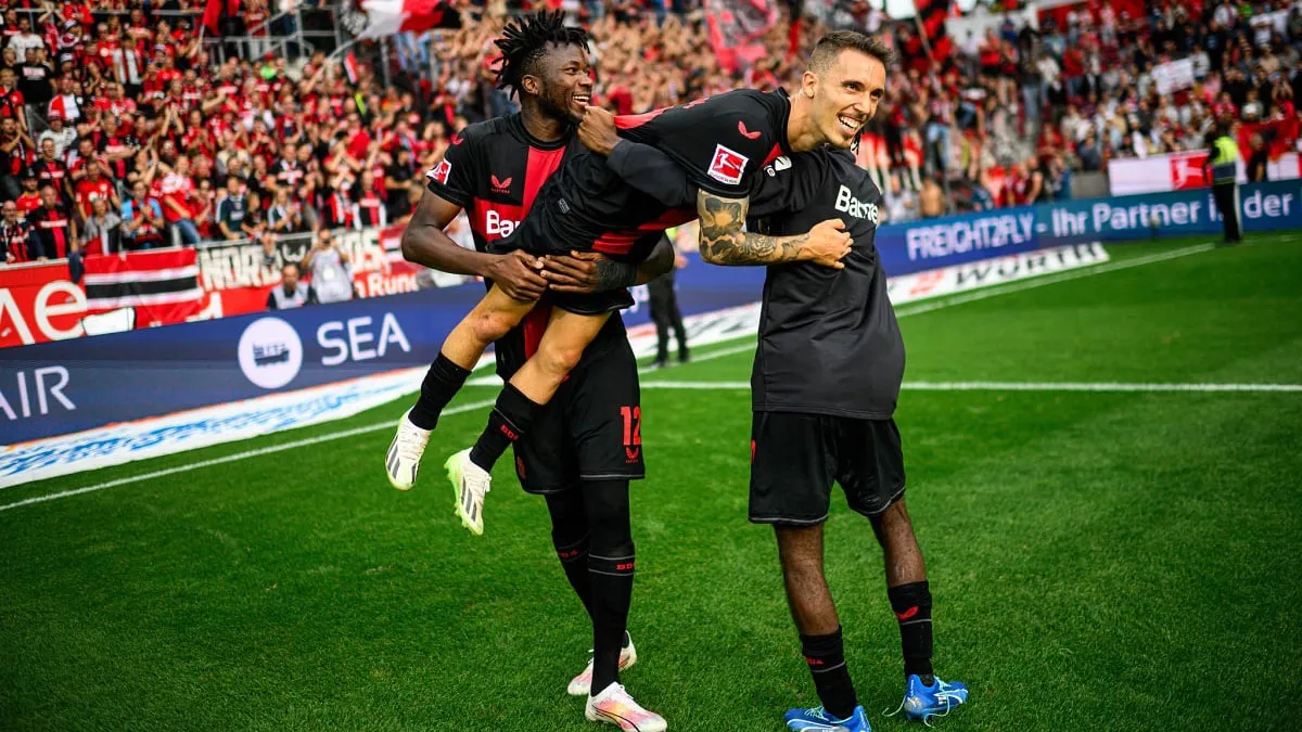O português Grimaldo é erguido por colegas de time, após marcar mais um gol pelo Bayer Leverkusen.