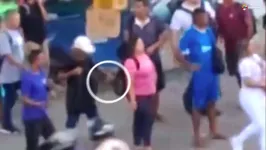 Momento em que homem põe a mão na mochila da mulher e retira algo