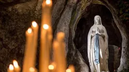 Velas acesas em frente à imagem de Nossa Senhora de Lourdes, na Gruta das Aparições.