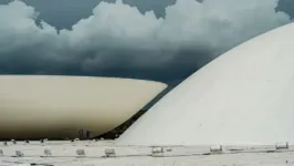 Cúpula da Câmara dos Deputados e do Senado Federal, no Conresso Nacional, com núvens, tempo fechado ao fundo.