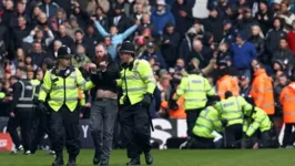 Torcedor envolvido na confusão que paralisou a partida entre West Brom e Wolves é conduzido por policiais ingleses.