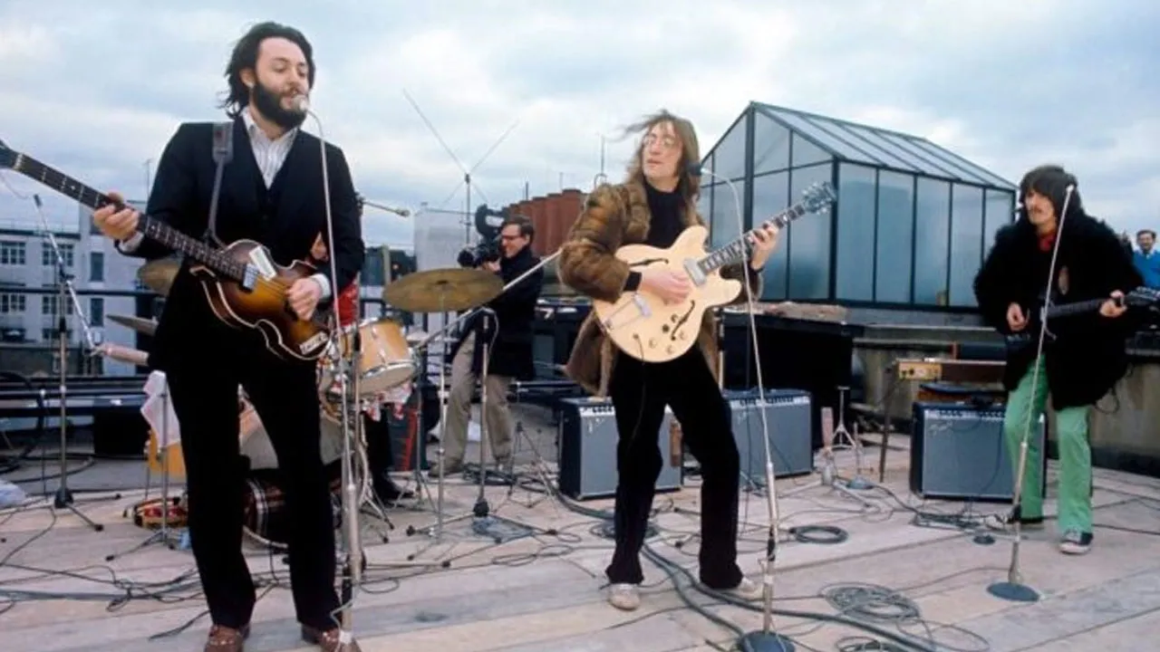 No topo do mundo da música: os Beatles em sua histórica última apresentação ao vivo no telhado da Apple Corps, capturada no filme 'Let It Be'. Uma cena inesquecível que ecoa através dos tempos.