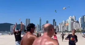 Chuva de dinheiro jogado de helicóptero atraiu dezenas de pessoas em praia de Balneário Camboríu neste domingo (21)