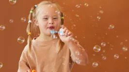 Criança com Síndrome de Down brincando de bolha de sabão.