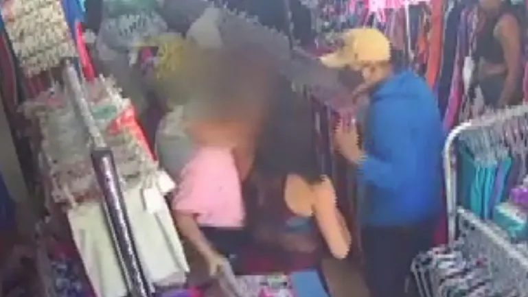 A proprietária (blusa rosa) atacada pelo bando durante o assalto