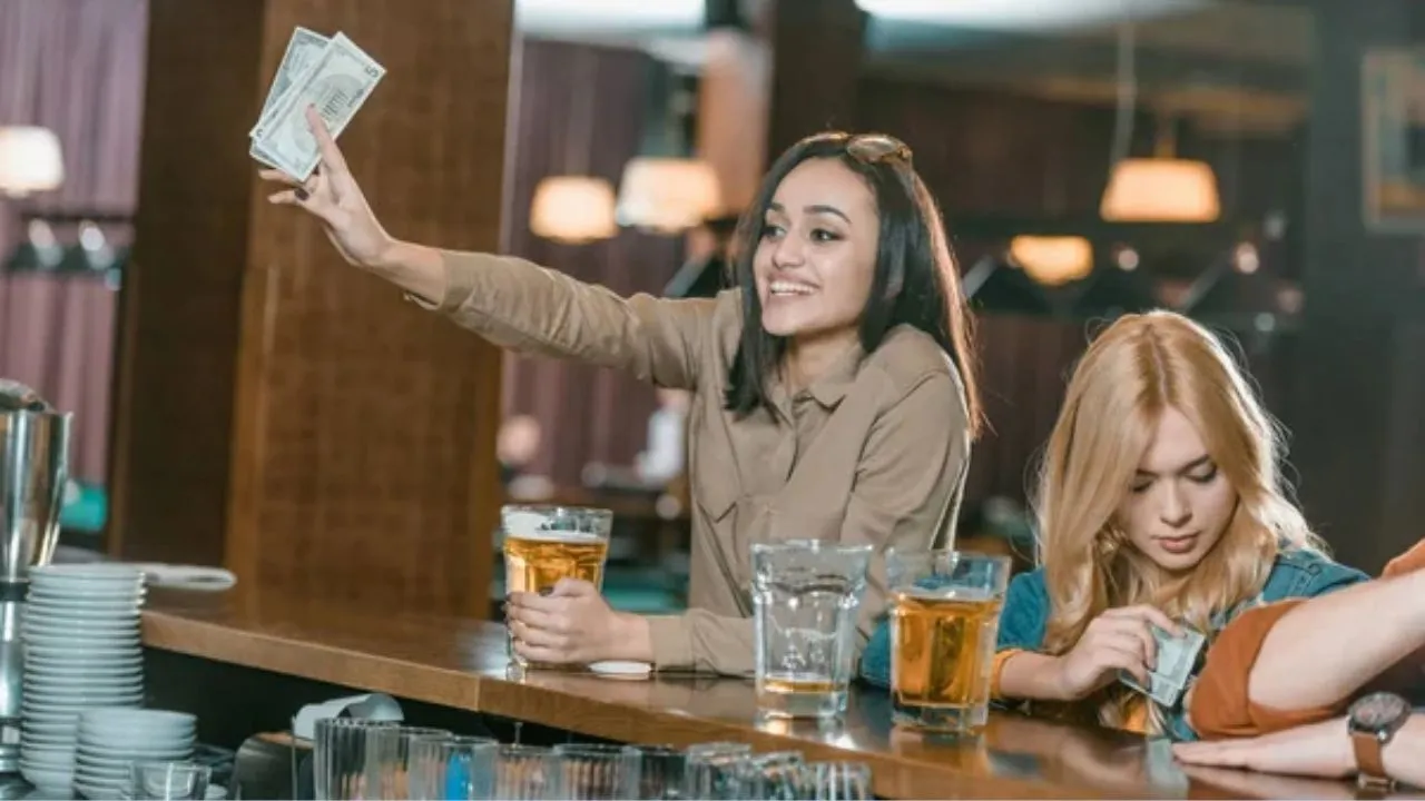 Na imagem, você pode conferir mulheres gastando dinheiro em um bar.
