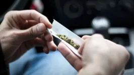 Homem fazendo cigarro de maconha no carro