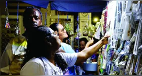 Lorena Cabral, pernambucana, fez questão de amarrar uma fitinha na grande da Basílica. Abaixo, a artesã Madalena Cordeiro, cuja produção é carregada de amor pela padroeira.