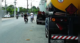 Caminhões estacionam impunemente na ciclofaixa e obrigam os ciclistas a se arriscarem em meio ao fluxo de veículos da via.