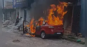 Carro pegando fogo em frente a residência que também é atingida