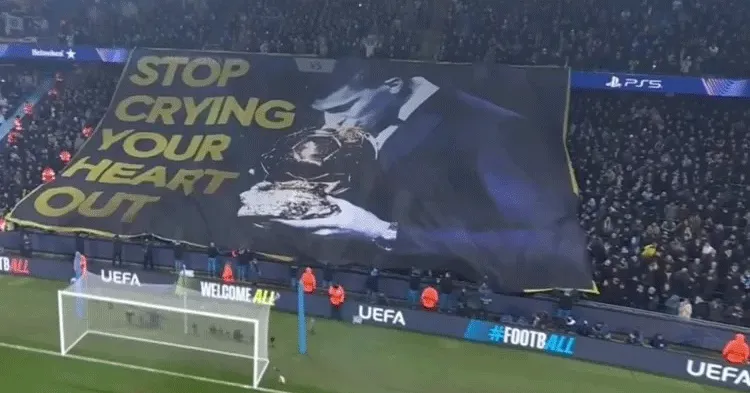 Torcida do City exibe faixa com imagem de Rodri beijando a Bola de Ouro antes da partida contra o Real Madrid na Champions League.