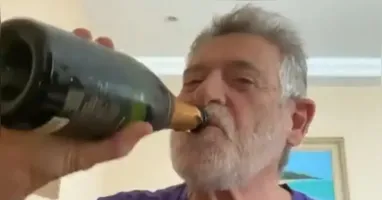 Ator aparece abrindo uma garrafa de champanhe ao som do hino nacional
