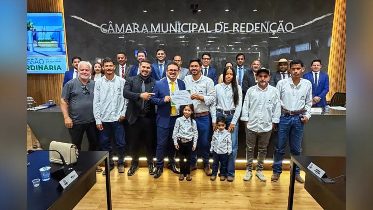 Weliton Ribeiro Gomes, o Timbó, ladeado por autoridades durante o recebimento da Moção de Aplausos na Câmara Municipal.