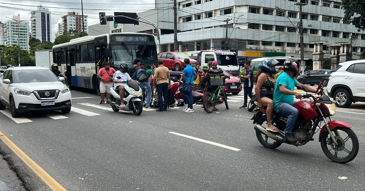 Pedestres prestam os primeiros socorros a motociclista após acidente com ônibus