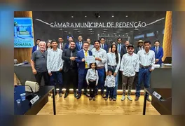 Weliton Ribeiro Gomes, o Timbó, ladeado por autoridades durante o recebimento da Moção de Aplausos na Câmara Municipal.
