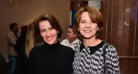 Vera Zimmermann e Luciana Ramanzini posam juntas ao pôr do sol em praia paradisíaca.