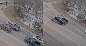 As imagens mostram uma picape e um SUV parados em um semáforo quando parte da pista cede.