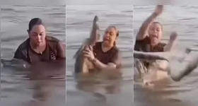 Mulher segura 'pedaço de tronco' em lagoa e descobre ser um jacaré.