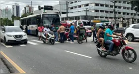 Pedestres prestam os primeiros socorros a motociclista após acidente com ônibus