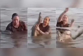 Mulher segura 'pedaço de tronco' em lagoa e descobre ser um jacaré.