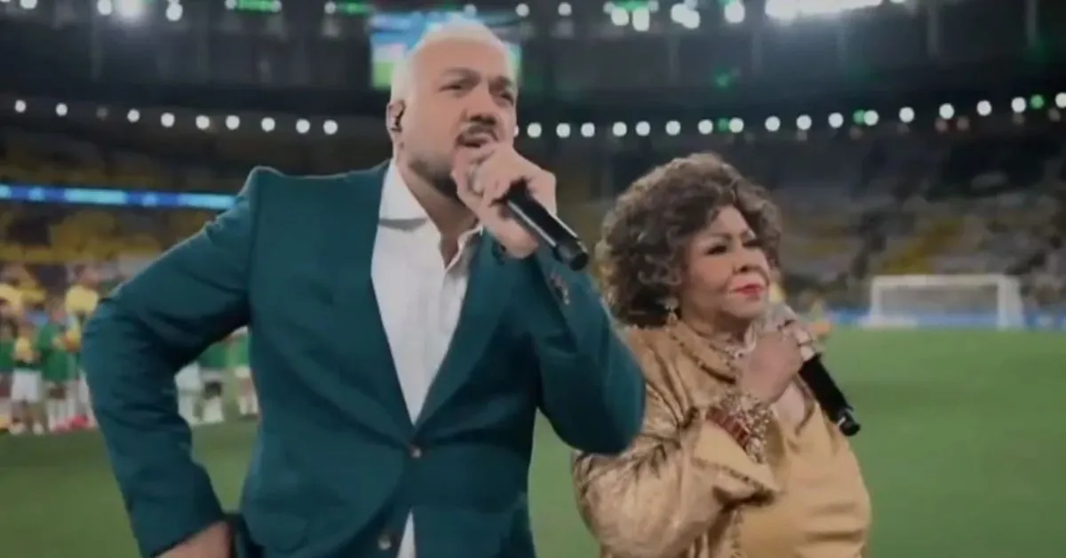 Belo e Alcione se atrapalham ao cantar o Hino Nacional no amistoso Brasil x Panamá