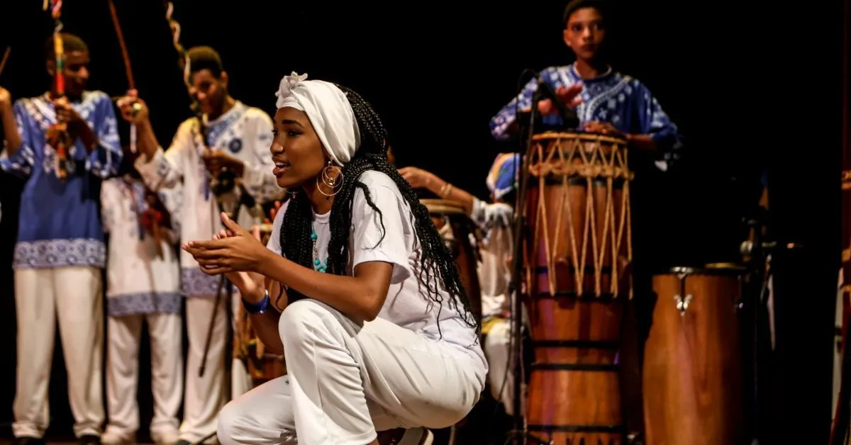 Com duração de uma hora, a montagem leva ao palco uma experiência cênico-musical que percorre a história da resistência do povo negro por meio da Capoeira Angola e de manifestações tradicionais como o Tambor de Crioula, o Bumba Meu Boi, o Samba e as tradições de matriz africana.