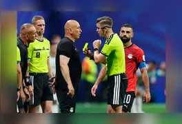 À beira do gramado, o técnico Hossam Hassan gesticula e reclama com a arbitragem francesa antes de ser advertido com o cartão amarelo.