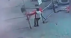 Câmera de segurança registra o instante em que o trabalhador sofre a descarga elétrica e fica preso ao portão de ferro.