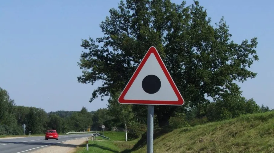 Descubra o que significa a placa triangular com ponto preto no Reino Unido e sua importância na sinalização viária.
