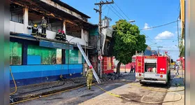 Bombeiros trabalham na operação de rescaldo após o incêndio destruir as estruturas da farmácia UltraPopular e da loja Fill a Fill na Cidade Nova.