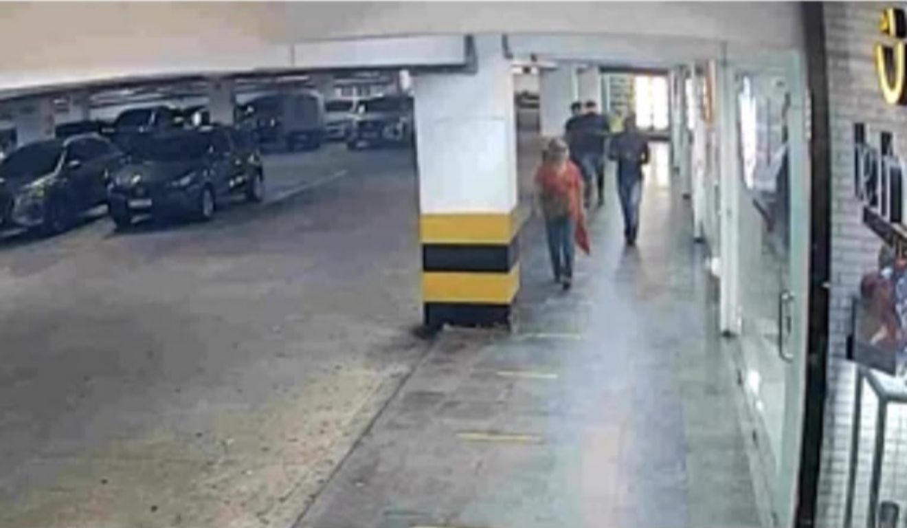 Câmeras de monitoramento mostram os suspeitos perseguindo a vítima (camisa laranja) em estacionamento