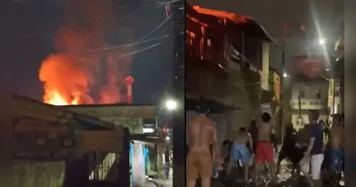 Casa atingida e moradores pegando água da vala para apagar